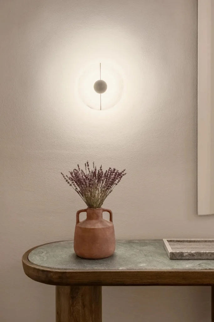 Console table with a lavender vase under a round wall light – IDYLI Architects
